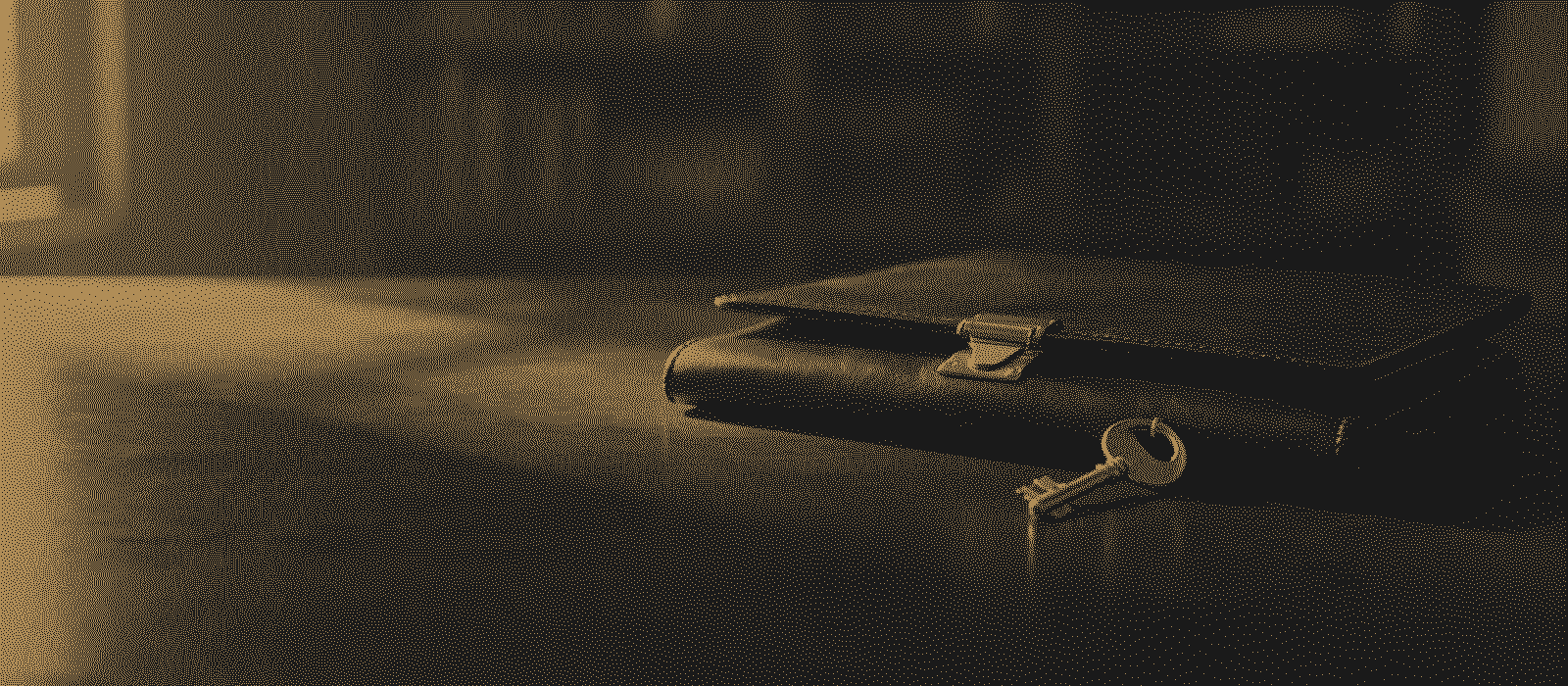 A closed leather folder with a brass clasp and a key on a desk, printed in gold dots on black