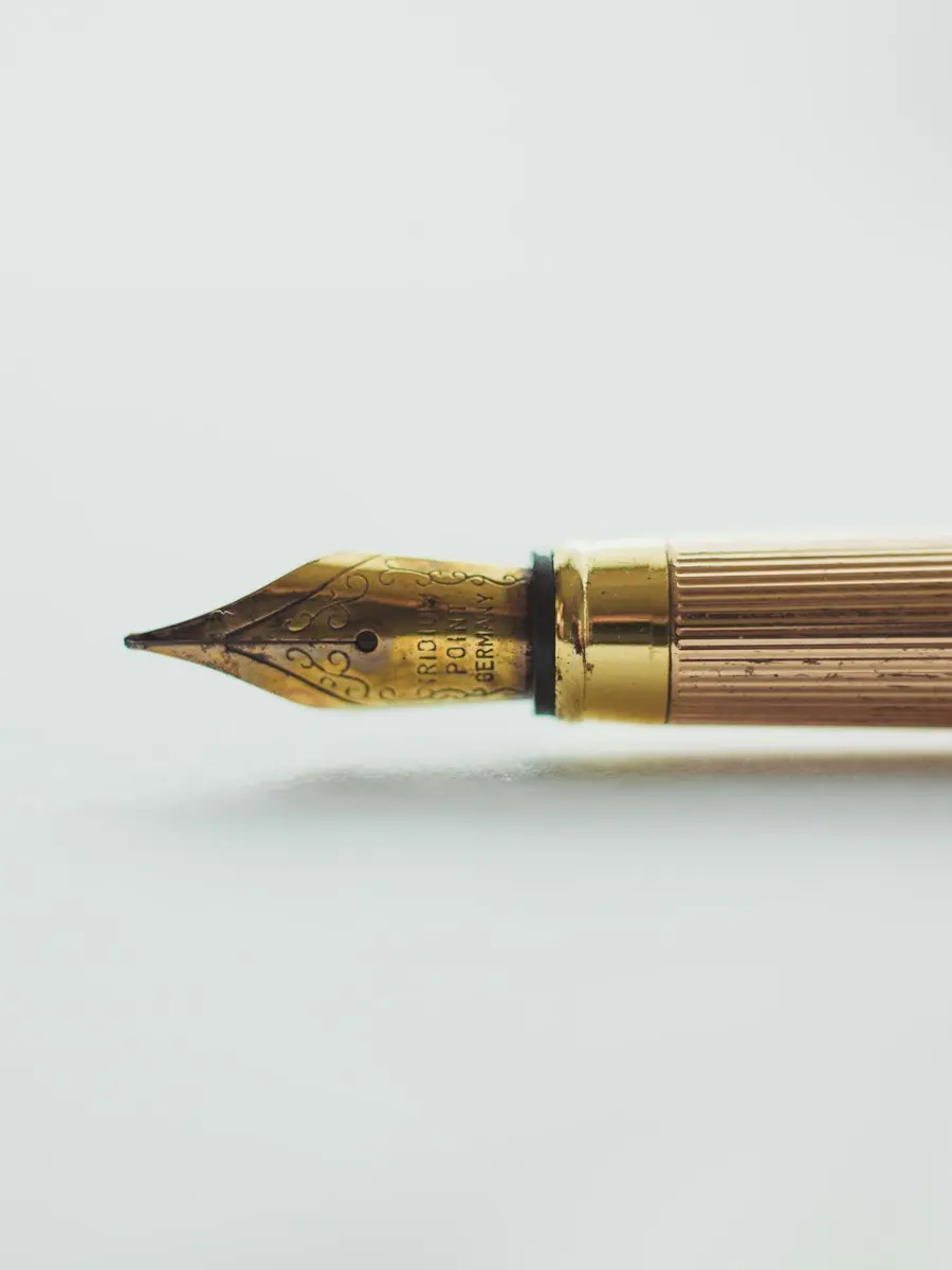 The gold nib of a fountain pen on white paper